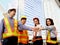 Group of four Asian man and woman engineers wear safety vest and helmet, put hands join together in downtown city, partnership