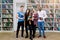 Group of four confident smiling multiethnical students, girls and boys in casual wear, posing in the library, holding