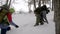 Group of four friends with big backpacks hiking in winter together, team going uphill.