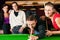 Group of four friends in a billiard hall playing s