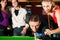 Group of four friends in a billiard hall playing s