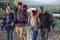 Group of four happy travelers are walking with the map and trying to find out the right way on mountain top at sunset