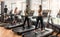 Group of four people running on treadmills in fitness gym