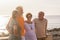 Group of four senior and mature people with a friendship at the beach talking and enjoying together - sea at the background