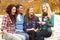 Group Of Four Teenage Girls Sitting On Bench