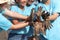 Group of four volunteer in blue t-shirt showing join hands covered mud dirty after planting sapling tree in deep mud at mangrove