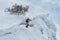 A group of freeriders arrived at the top of the mountain on a snowmobile. One skier jumps off a cliff