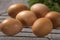 Group of fresh chicken eggs on a metallic grille with fresh green herbs in background