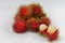 A group of fresh red rambutan on a white background with peeled fruits which are sold on the Thai marke