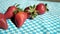 Group of fresh strawberries on a blue checkered tablecloth