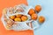 Group of fresh tangerines in the white string bag on the orange background isolated. No plastic, eco zero waste concept