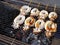 group of fresh white octopus skewers grilling on steel grate charcoal stove