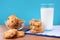 Group of freshly baked biscuits with cereal and raisins and glass of milk on blue towel