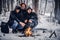 A group of friends of backpackers went on a hike in the snowy forest, warmed sitting by the fire in the middle of the