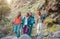 Group of friends with backpacks doing trekking excursion on mountain - Young tourists walking and exploring the wild nature