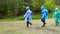 Group of friends with backpacks in raincoat walk one after another in forest in rainy weather. Hike