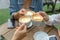 Group of friends cheers with latae cup in cafe bar with phone on table sitting outdoor at cafe - Young girl group having fun