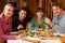 Group Of Friends Enjoying Meal In Alpine Chalet