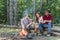 Group of friends enjoying picnic in the forest. Tourists relaxing. Happy friends enjoying bonfire in nature. Friends