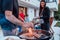 A group of friends and family barbecue together in the evening on the terrace in front of a large modern house