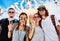 Group of friends in front of temple in thailand waving at camera