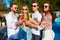 Group of friends having fun at poolside summer party, clinking glasses with colorful summer cocktails outdoors near