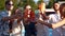 Group of friends having fun at poolside summer party clinking glasses with summer cocktails at camera near swimming pool