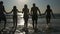 Group of friends holding hands and walking in the sea at twilight in slow motion