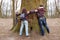 Group of friends hugging giant tree trunk and holding hands during hiking excursion. Tree hugging, tourism, ecology