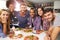 Group Of Friends Making Pizza In Kitchen Together