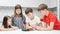 Group of friends play toy fishing on kitchen table. Smart boy hold fishing rod and pick up playthings from plate.