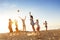 Group of friends plays ball sunset beach