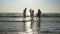 Group of friends running towards the sea and dancing with their feet in the cold water