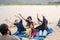 Group of friends sitting on beach and singing. One man is playing guitar. Summer holidays, vacation, relax and lifestyle concept