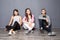 Group of friends sitting on floor on gray background