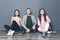 Group of friends sitting on floor on gray background