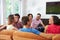 Group Of Friends Sitting On Sofa Watching Soccer Together