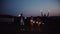 A group of friends with sparklers standing outdoors at dusk. Slow motion.