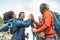 Group of friends stacking hands on peak of mountain - Young tourists trekking and exploring the wild nature