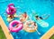 Group of friends swim on inflatable toys in pool