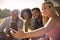 Group Of Friends On Vacation Sitting On Porch Of Countryside Cabin Drinking Beer And Taking Selfie 