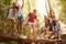 Group Of Friends On Walk Balancing On Tree Trunk In Forest