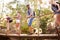 Group Of Friends On Walk Crossing Wooden Bridge In Forest