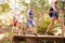 Group Of Friends On Walk Crossing Wooden Bridge In Forest