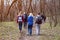 Group of friends walking with backpacks in spring forest from back. Backpackers hiking in the woods. Adventure, travel