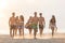 Group of friends walking on the beach at sunset.