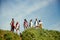 Group of friends walking in meadow on warm, sunny, summer day. Young people standing on hill and enjoying nature