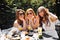 Group of friends in white having breakfast in garden at table with food and communicating, laughting concept