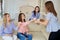 A group of friends of young girls talk at a meeting in a room.