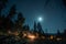 Group gathered around campfire under the moonlit sky at midnight